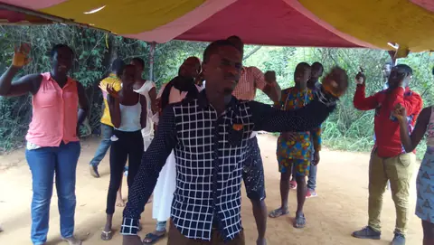 Young people worshipping outdoors under a canopy